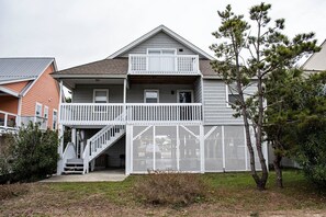A two-story house with a balcony, a staircase, and a fenced yard. - 4 Bedroom Third Row Cozy Beach Cottage (Ocean Isle Beach)