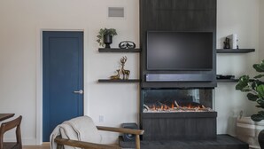 A living room with a fireplace, a television, and a blue door. - The Big Lohbow-Ski Haus (Revelstoke)