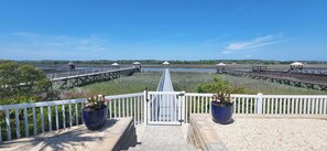 A waterfront property with a long wooden pier, white railings, and potted plants. - Large Luxury Property on Marsh Private Pool Hot Tub (Ocean Isle Beach)