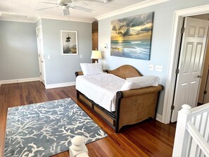 A bedroom with a bed, a ceiling fan, a painting, and a door. - Large Luxury Property on Marsh Private Pool Hot Tub (Ocean Isle Beach)