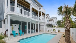 Une maison à deux étages dotée d’un patio couvert et d’une piscine.