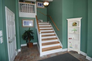 A staircase with white railings and wooden steps, leading to a landing with a small shelf and a framed picture. - 4 Bedroom 4 Bath House Private Pool Close to Beach (Ocean Isle Beach)