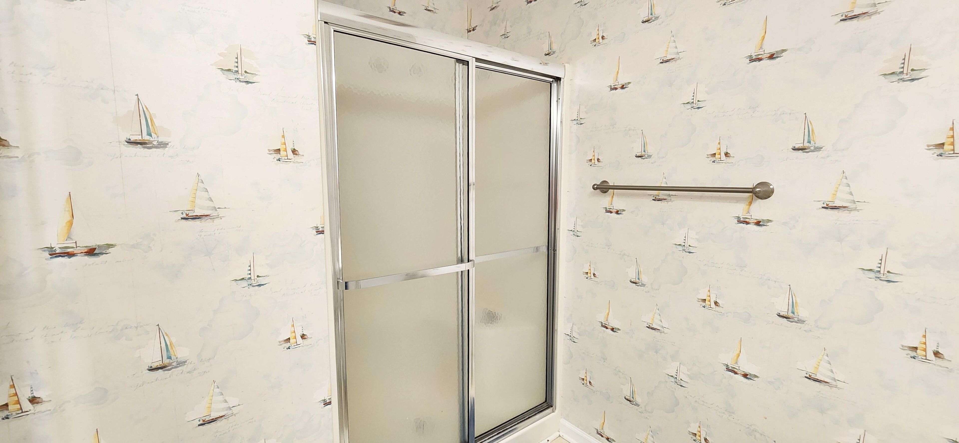 A bathroom with a shower door and a towel rack.