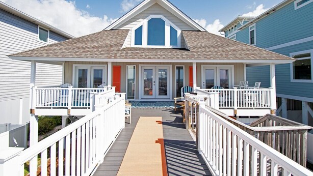 Una casa sulla spiaggia con una veranda coperta, un piccolo portico e vista sull'oceano.