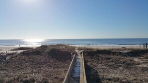 Un sentiero sulla spiaggia che conduce verso l'oceano, con cielo sereno.