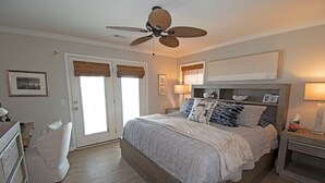 Ein Schlafzimmer mit einem großen Bett, einem Deckenventilator, einem Nachttisch und einem Schreibtisch.
