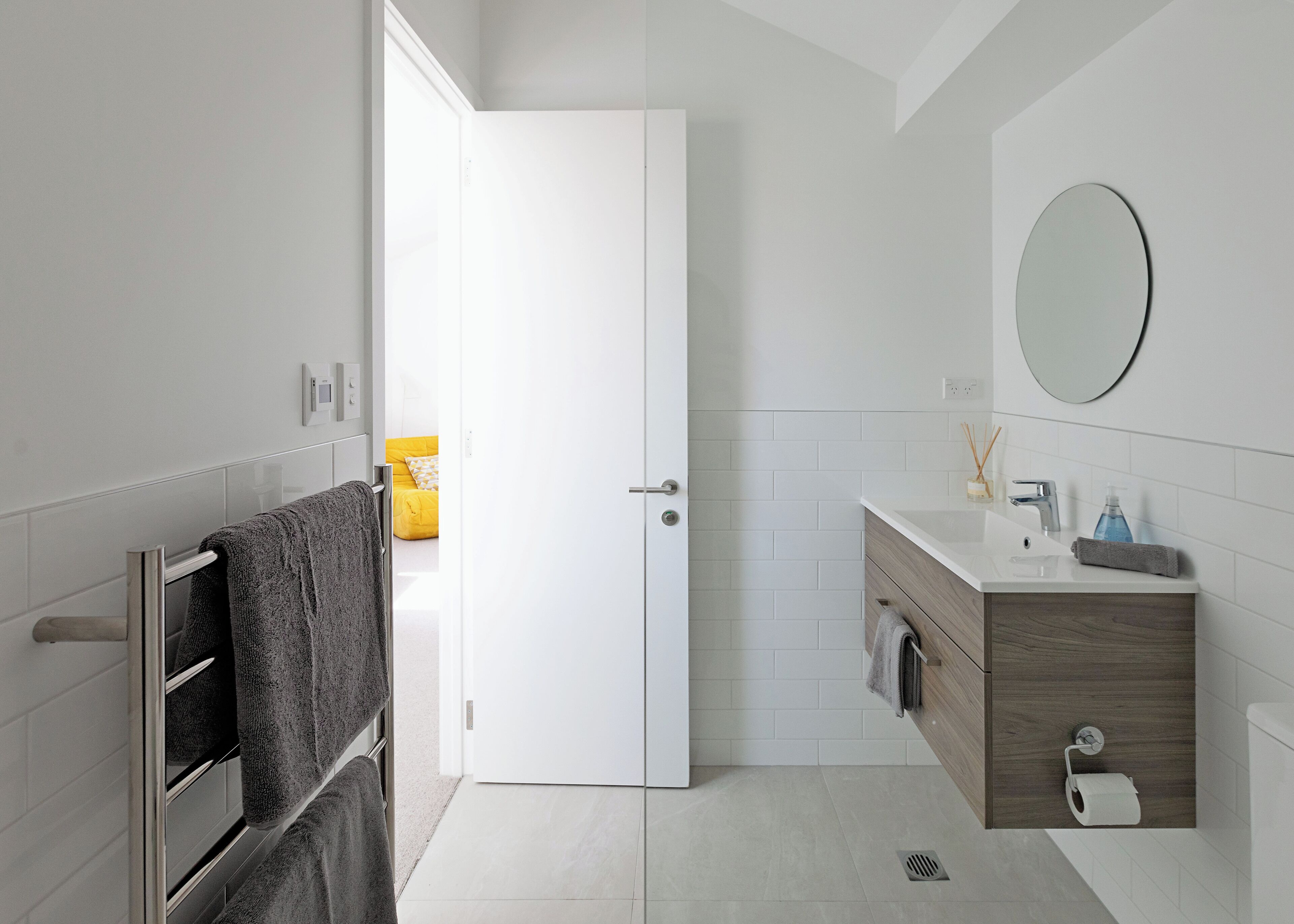 Un bany modern amb un lavabo blanc, mirall i paraigua de tovalloles.