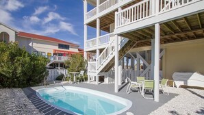 A swimming pool with a deck area, outdoor seating, and a multi-level structure with stairs. - 5 bedroom house with pool, close to center of town (Ocean Isle Beach)