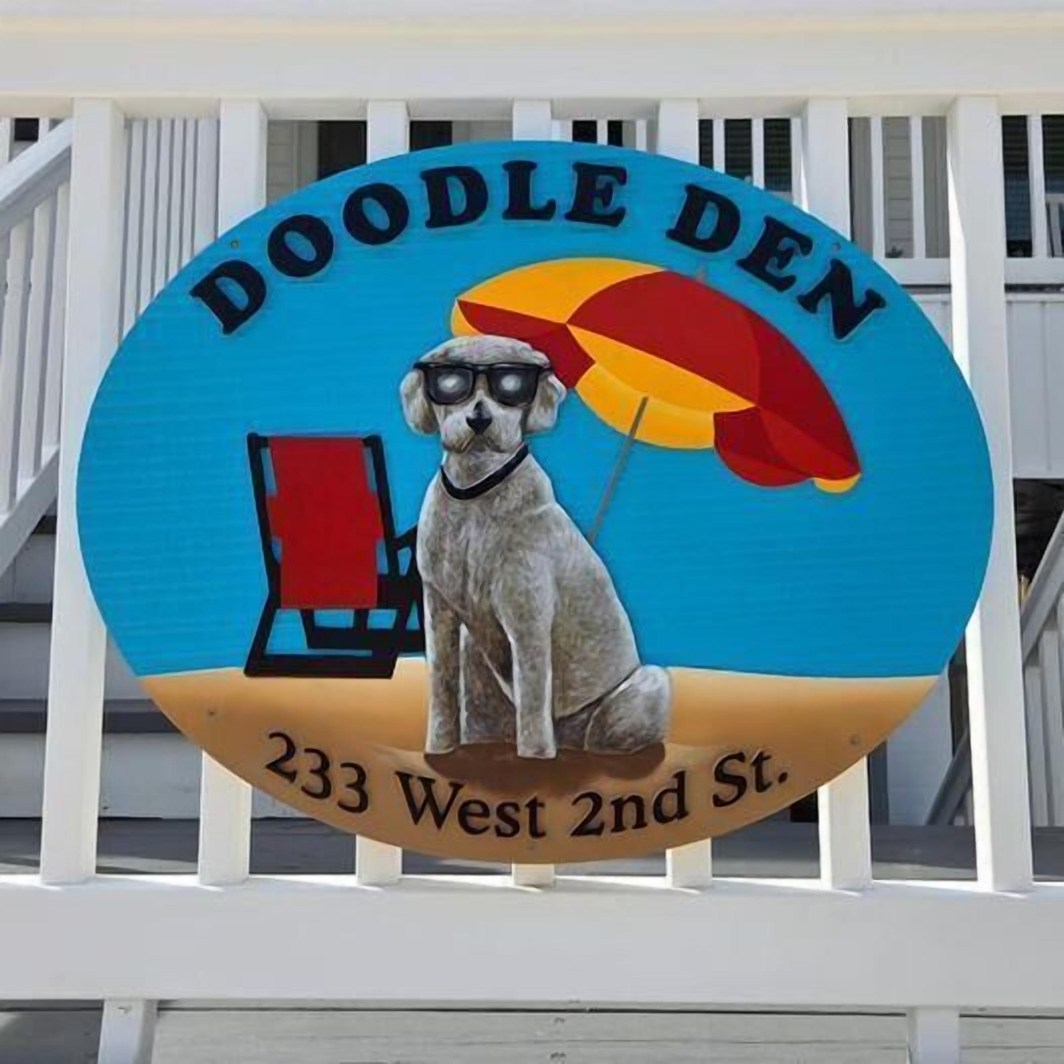 A sign with a dog wearing sunglasses and holding a beach umbrella, labeled 'DOODLE DEN 233 West 2nd St.'
