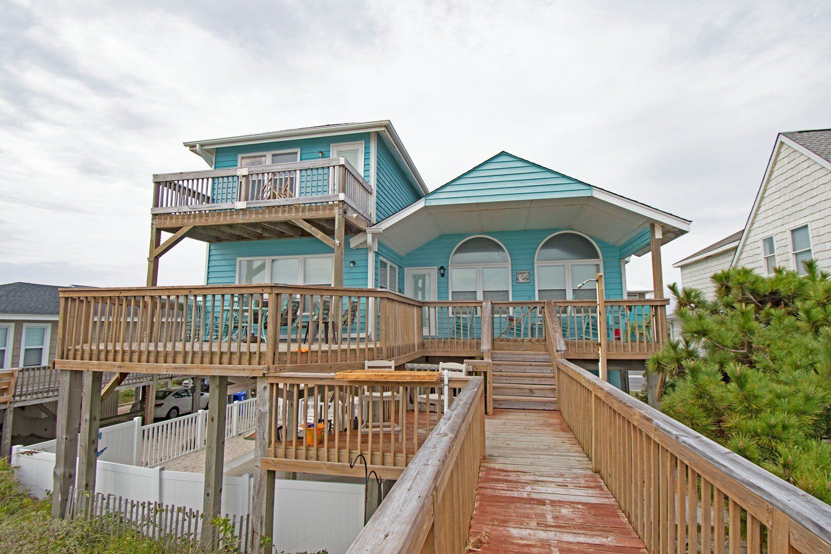 A two-story house with a wooden deck and a covered porch.