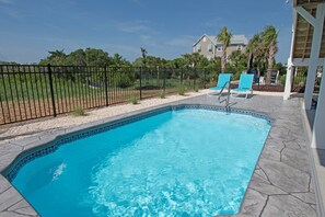 Una piscina rectangular con borde de azulejos, rodeada por una valla de metal negro.