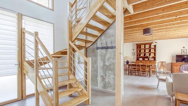 Un vaste espace de vie comprenant un escalier en bois, un coin repas et une bibliothèque.