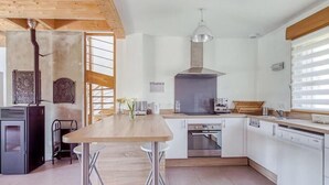 Une cuisine moderne avec des meubles blancs, une table en bois et un four encastré.