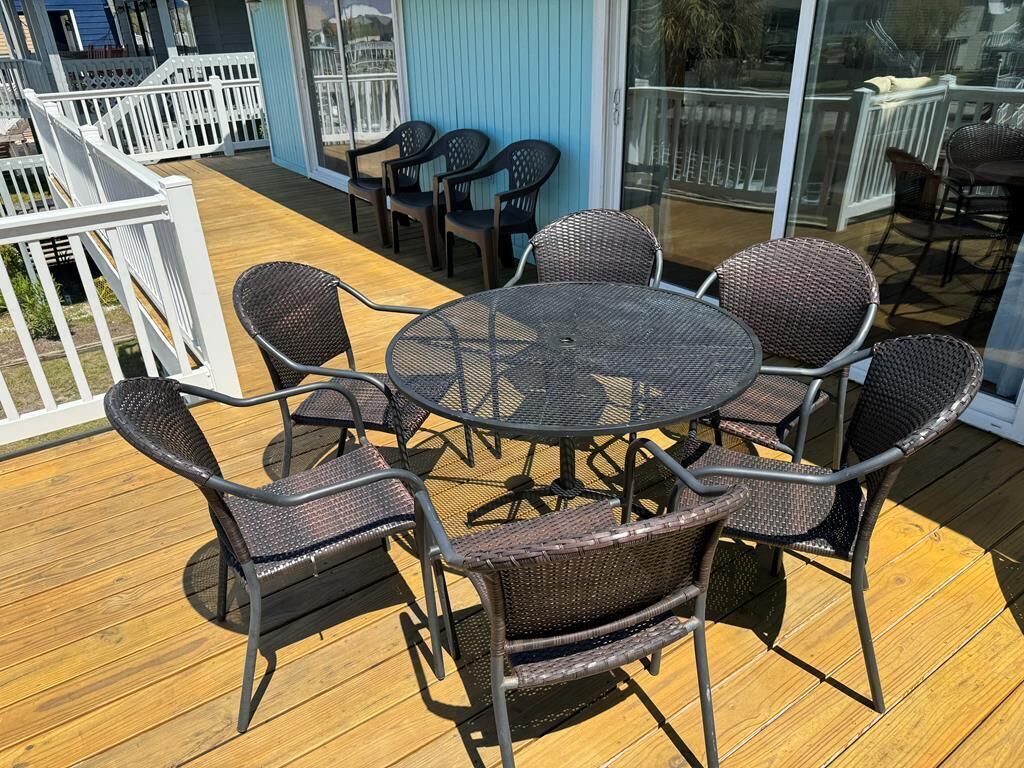 Une terrasse avec une table ronde et six chaises en osier.