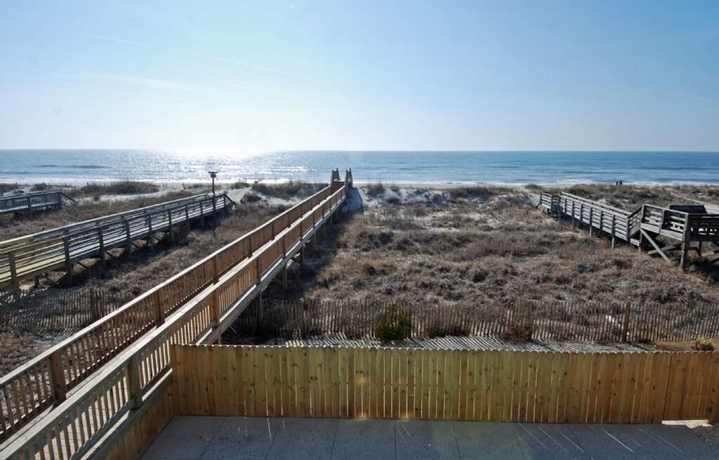 A wooden boardwalk leading to the beach with a clear view of the ocean.