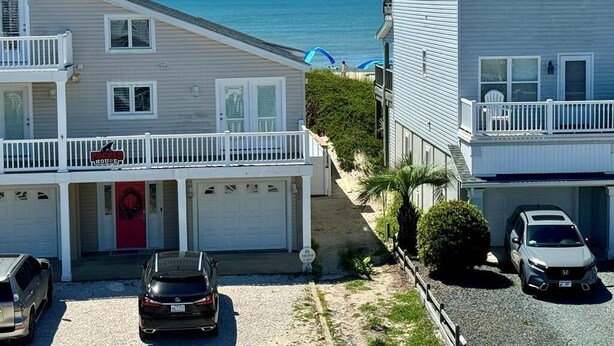 Una propiedad frente a la playa con una construcción de dos pisos, un porche cubierto y un garaje.