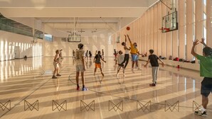 Una cancha de baloncesto con varios jugadores, un aro de baloncesto y un espejo grande en la pared.