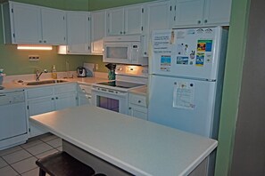 A kitchen with white cabinets, a microwave, a stove, a refrigerator, and a sink. - 3 br, 2 ba oceanfront condo, bed linens provided (Ocean Isle Beach)