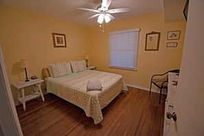 A bedroom with a bed, a nightstand, a lamp, a ceiling fan, and a window with blinds. - 3 br, 2 ba oceanfront condo, bed linens provided (Ocean Isle Beach)