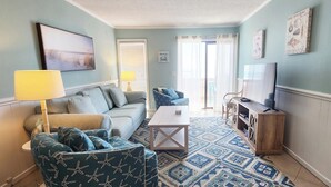 Una sala de estar con un sofá, una mesa de centro, un televisor y una alfombra estampada.
