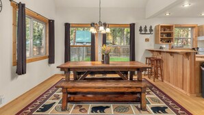 A spacious kitchen with a wooden table, bar stools, and a large window. - Cozy cabin, dogs ok, hot tub, & fireplace (Leavenworth)