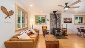 A cozy living room with a leather sofa, wooden coffee table, and a stone fireplace. - A cozy dog friendly cabin, sleeps 6 with a hot tub (Leavenworth)