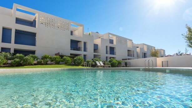 Ein modernes Hotel mit Schwimmbad, klarem, blauem Wasser und blauem Himmel.