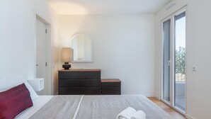 Ein Schlafzimmer mit Bett, Schminktisch, Spiegel und einer Schiebetür zum Balkon.