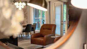 Una sala de estar moderna con un sillón de cuero, una mesa de comedor con sillas y un ventanal grande.