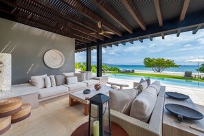 Ein moderner Außenbereich mit Sofa, Couchtisch und Blick auf den Ozean.