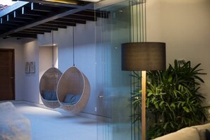 Ein modernes Interieur mit hängenden Korbstühlen, einer Stehlampe und einem Blumentopf.