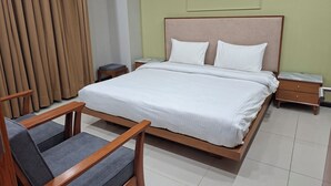 A hotel room with a bed, bedside tables, a chair, and a curtain. - Charming 1-bedroom apartment with AC in vibrant Islamabad (Islamabad)