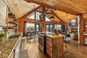 Eine geräumige Küche mit einer großen Kochinsel, Holzboden und einem Kamin aus Stein.