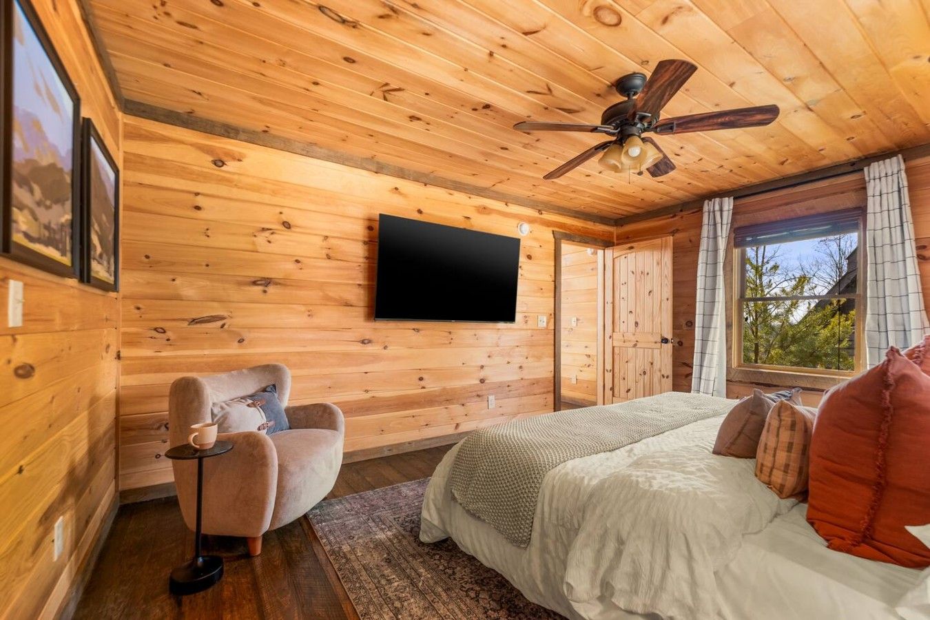 Una habitación acogedora con cama, una silla, un televisor y un ventilador de techo.