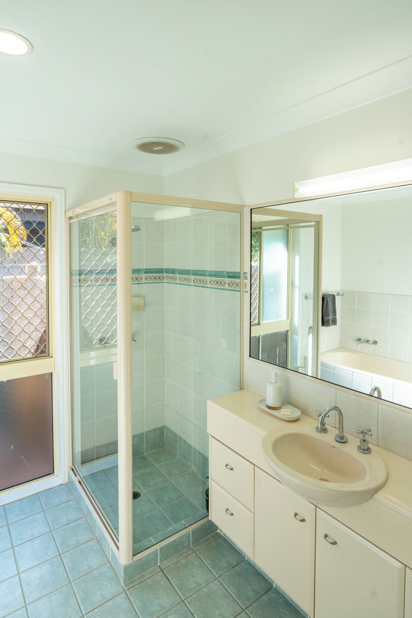 Ein Badezimmer mit Duschkabine, Waschbecken und Spiegel.