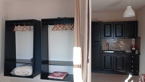 Una cucina compatta con pensili scuri e una lampada a sospensione bianca.