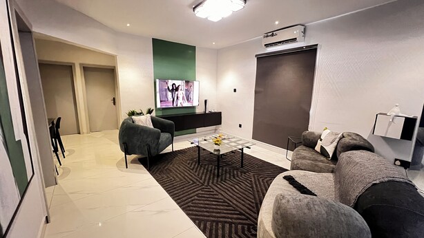 Una sala de estar moderna con un televisor de pantalla plana, un sofá, una mesa de centro y una alfombra estampada.