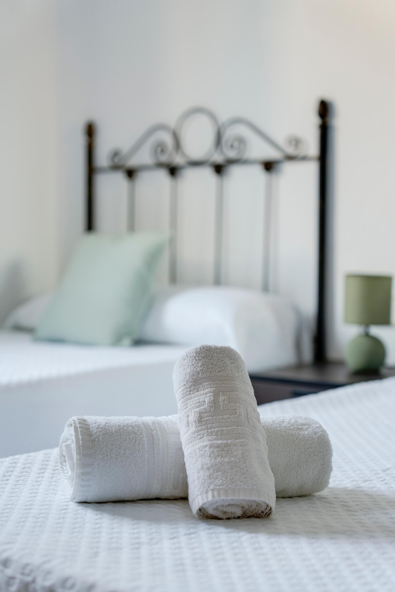 Un lit bien fait, avec du linge de lit blanc et deux serviettes enroulées.