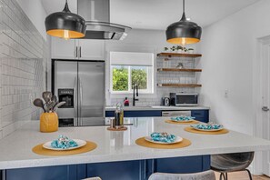A modern kitchen with a central island, stainless steel appliances, and pendant lighting. - The Design District Pool House (Miami)