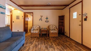 A cozy room with a blue sofa, two wicker chairs, a small table, and a wooden floor. - Waterfront Cabin for up to 8 (Benton)