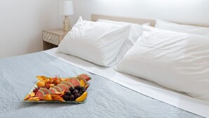 A neatly made bed with white linens and pillows, a bedside table with a lamp, and a fruit platter on the bed. - Le Plaza Modern Escape Near Thessaloniki Center (Kalamaria)