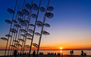 Escena de playa con sombrillas y gente al atardecer.