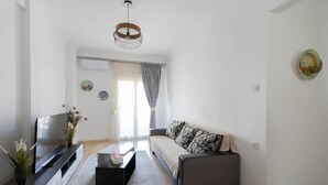 A modern living room with a sofa, TV, and decorative items. - Le Plaza Modern Escape Near Thessaloniki Center (Kalamaria)