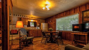 A cozy cabin interior with a wooden interior, a dining area, a kitchen with a refrigerator, and a television. - Waterfront Cabin for up to 6 (Benton)