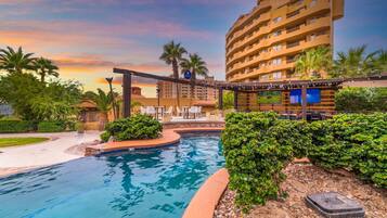 Un hotel con piscina, mobiliario exterior y vistas al atardecer.