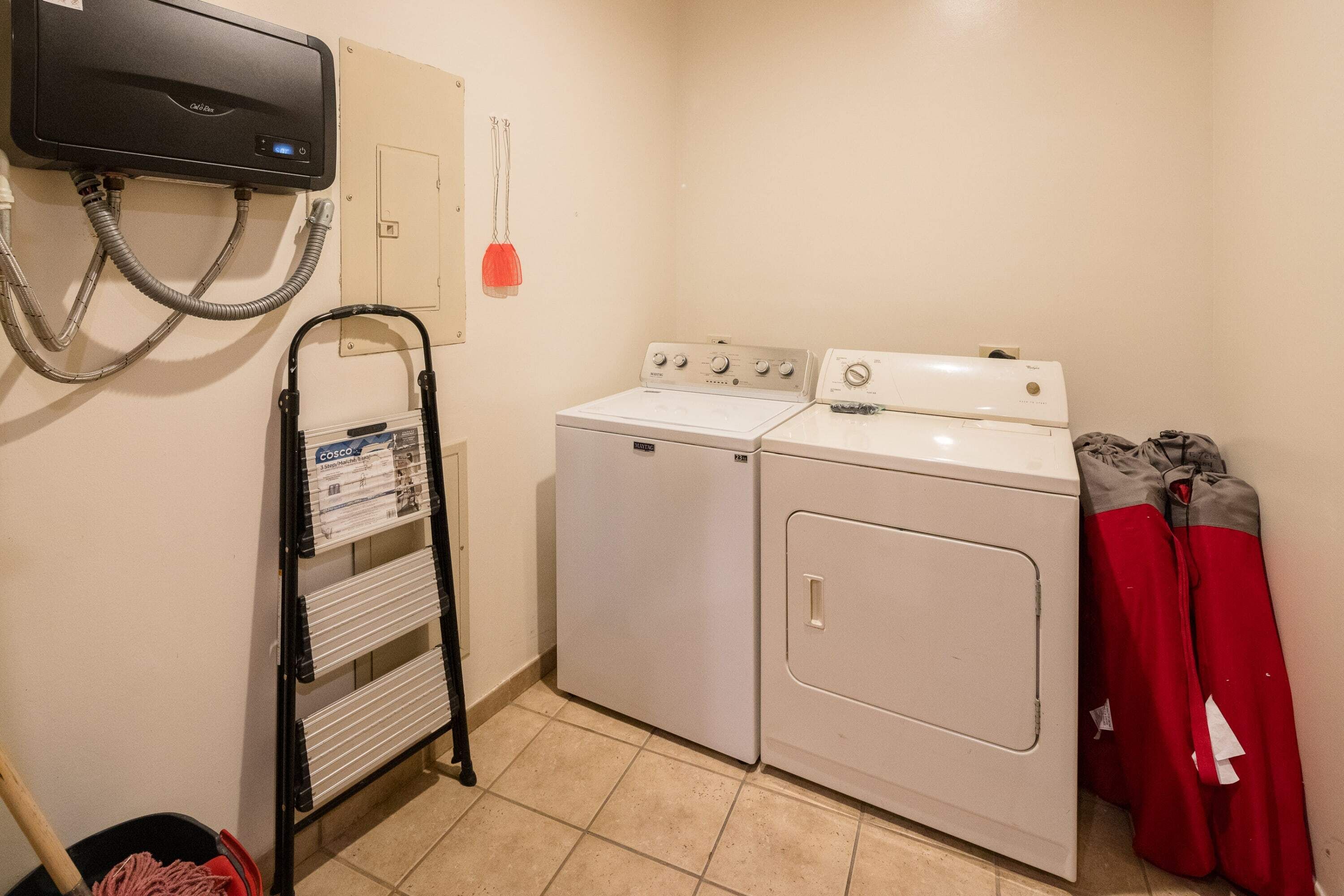 Un espace buanderie équipé de deux machines à laver, d’un sèche-linge et d’un radiateur fixé au mur.