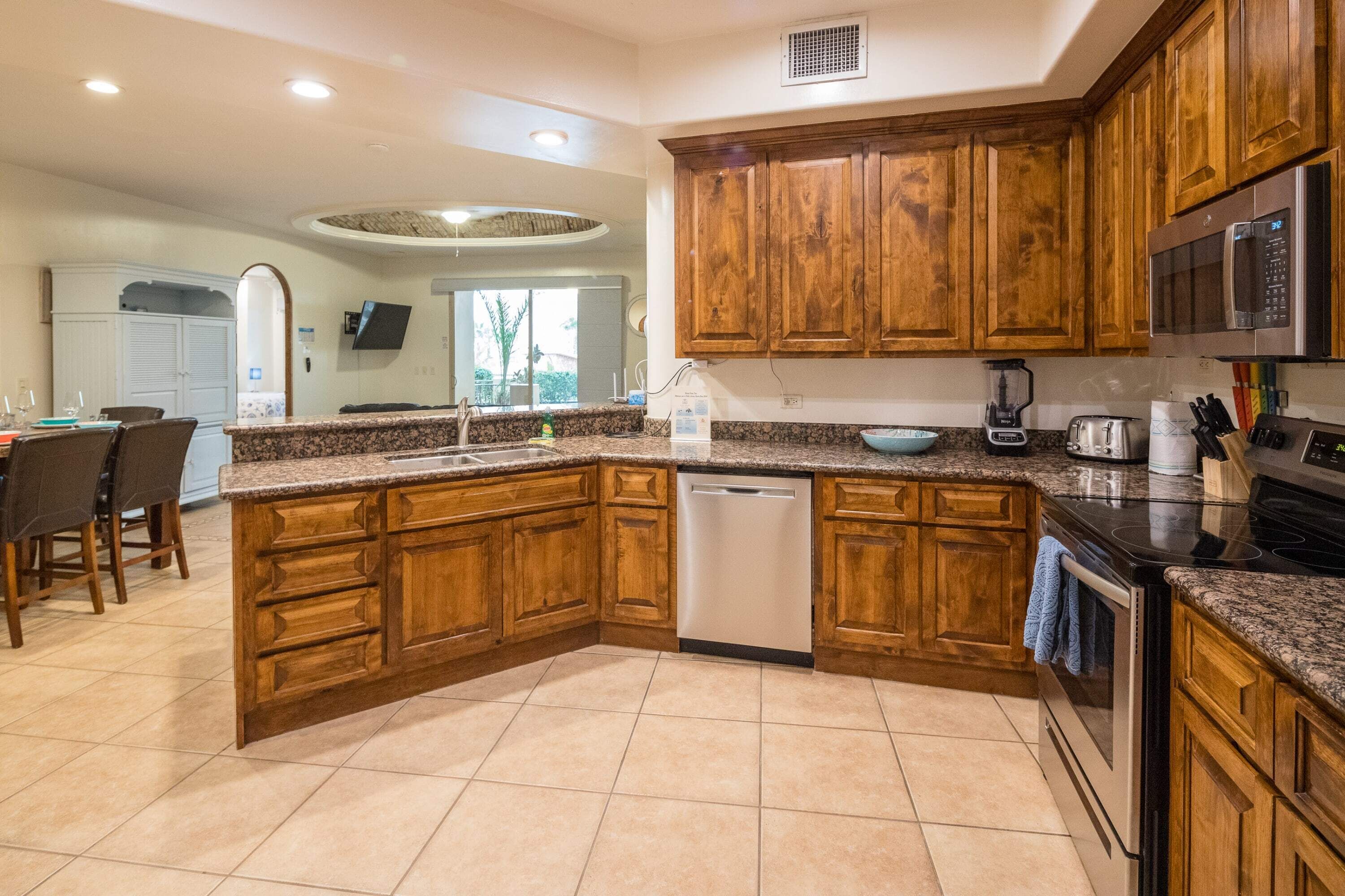 A kitchen with wooden cabinets, granite countertops, a dishwasher, a microwave, and an oven.