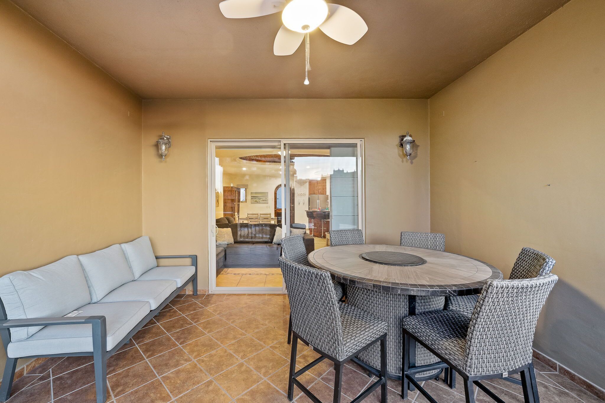 Une terrasse avec une table ronde et des chaises, un canapé et un ventilateur de plafond.
