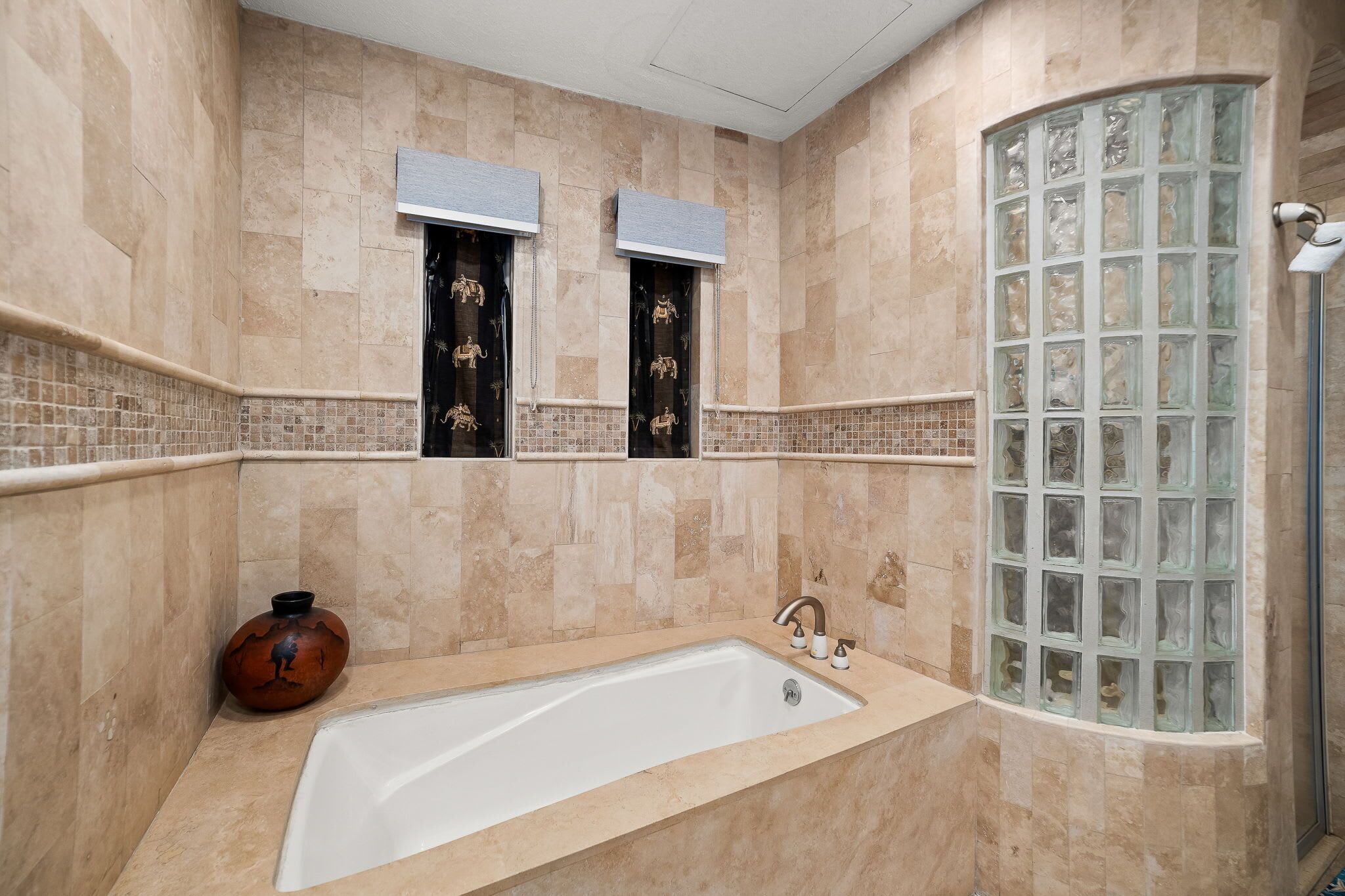 A bathroom with a large bathtub, a shower with a glass enclosure, and decorative tiles.