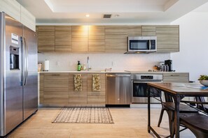 A modern kitchen with wooden cabinets, stainless steel appliances, and a dining area with a table and chairs. - High Rise Condo Water Views Walker's Paradise (Miami)